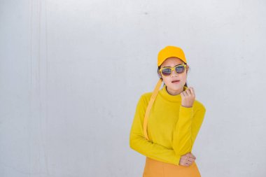 Güzel Asyalı kadın portresi, kirli beyaz duvarda sarı kumaşlar içinde, hippiler sarı şapka takıyor, Taylandlılar fotoğraf çekiyor.