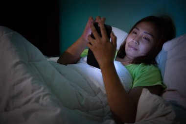 Asyalı kadın gece yatakta akıllı telefon oynuyor, Taylandlılar, sosyal medya bağımlısı, bütün gece internet oynuyor.
