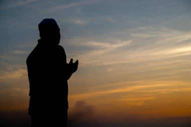 Siluet Genç Asyalı Müslüman adam gün batımında dua ediyor, Ramazan festivali konsepti