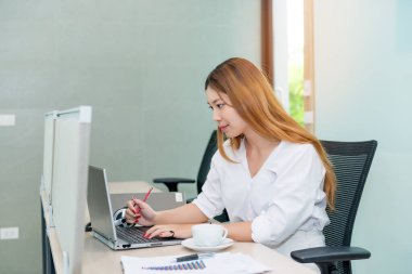 Ofiste çalışan ve kahve içen Asyalı kadın.