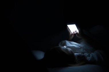 Asyalı kadın gece yatakta akıllı telefon oynar, Taylandlılar, sosyal bağımlılık.
