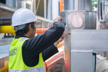 Büyük bir fabrikanın atık su yönetim sisteminde Asya Bakım Mühendisi, Tayland 'daki ısıtma sistemi ekipmanlarının teknik verilerini kontrol ediyor.