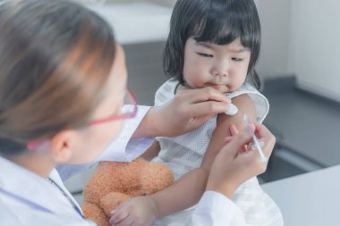 Solunumunu ve kalbini kontrol etmek için steteskop kullanan Asyalı bir doktor, Taylandlı çocukların sağlığını kontrol ediyor.