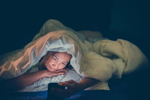 Asian woman play smartphone in the bed at night,Thailand people,Addict social media,Play internet all night