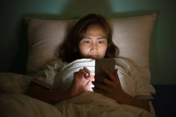 Asian woman play smartphone in the bed at night,Thailand people