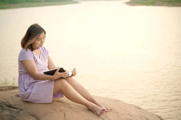 若いです妊娠中の女性読書本上の岩側ダム 暖かいトーン ヴィンテージスタイル セピア — ストック写真