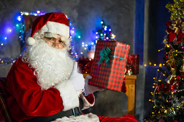 Santa claus holding gift box at home,Sit on chair think about plan for sent gift box for give children