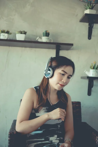 Asian woman sit listen song from headphone in coffee shop vintage style