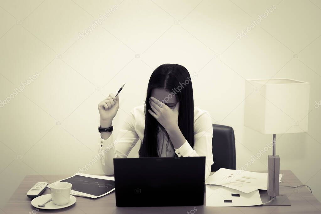 Businesswomanman stress from hard work on the desk at office dark tone,thailand people