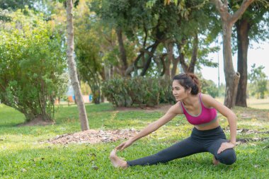 Asyalı zayıf kadın sabah antrenmanından önce ısınıyor, zayıf kız yaşam için egzersiz yapıyor, seçici odaklanma, parlak güneş ışığı, Taylandlılar...