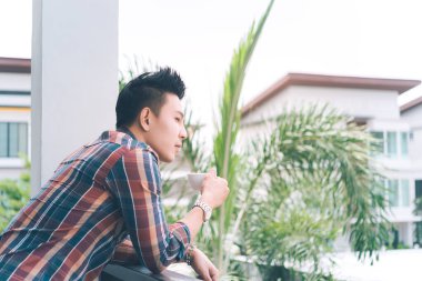 Balkonda kahve içen yakışıklı genç adam, genç, modern, modaya uygun, genç kızların rüyası.