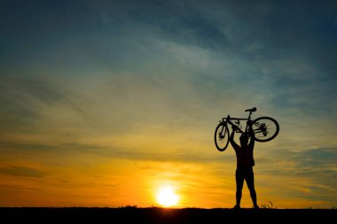 Gün batımında bisikletli Asyalı yakışıklı bir siluet.