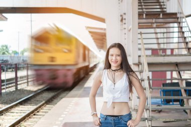 Tren istasyonundaki bulanık tren arkaplanıyla demiryolunda duran hoş bir kadın.
