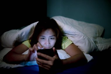 Asyalı kadın gece yatakta akıllı telefon çalar, Taylandlılar...