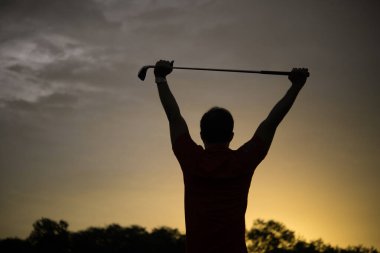 Siluet Asyalı golfçü Tayland halkının güzel günbatımında golf oynuyor.