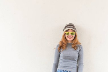 Beyaz duvarda hippi bir kızın portresi, modern bir gencin yaşam tarzı, gözlük takan havalı hippi öğrenci kadın.