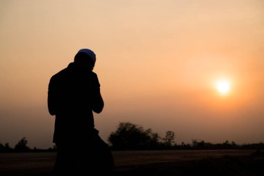 Silhouette Young asian muslim man praying on sunset,Ramadan festival concept clipart