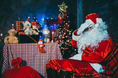 Noel baba holding hediye evde kutusunda, gönderilen hediye kutusu plan vermek çocuklar için sandalye düşünmek oturmak