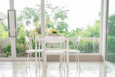 Oturmak için beyaz masa ve sandalye güneşli bir günde kitap okumak, rahatlamak, parlak güneş ışığı