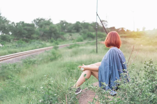 悲しい美しい女性は明るい太陽の光フィルムトーンと岩側の鉄道の方法に座る — ストック写真