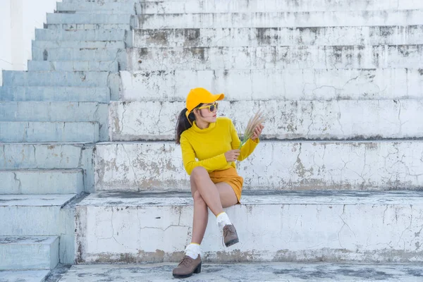穿着黄色衣服的美丽的亚洲女人的画像 希波斯特女孩在楼梯上戴着黄色的帽子拍照 泰国人的色调是黄色的 — 图库照片
