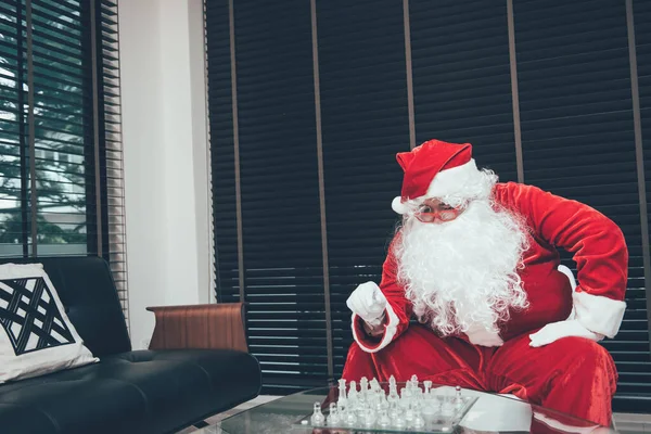 Lonely Santa Claus playing chess alone with sadness.