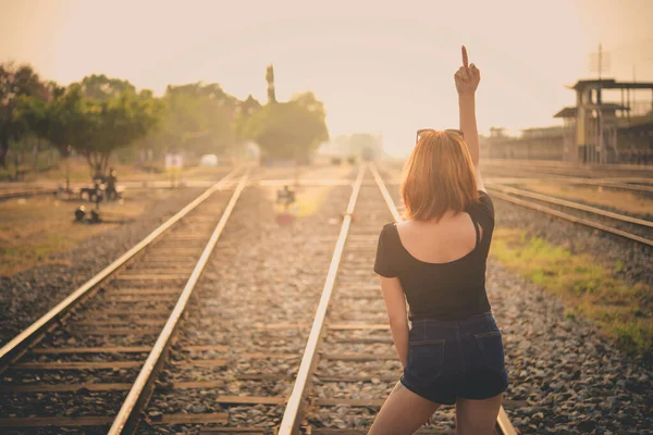 スポーティーな女の子が真ん中の指を見せて鉄道で頭の上でファックしてる屋外面白いライフスタイルの肖像画 残忍なの概念 反乱者 パンク 卑猥な 美しいタイの女の子 タイの女性黄金の髪 ヒップスターの女の子 — ストック写真