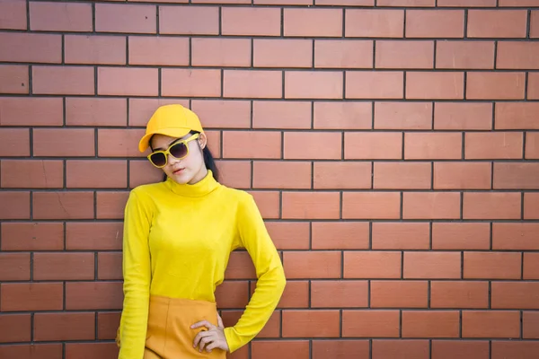 黄调的亚洲嬉皮士女郎 身披砖墙底色 — 图库照片