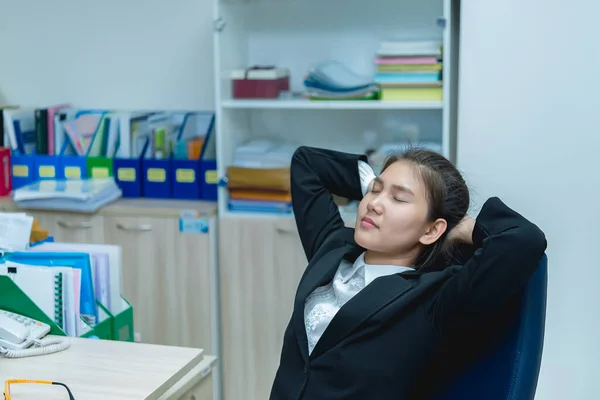 Asian officer woman stretching body at the desk of office from back angle,Thailand people,Businesswoman tired from hard work