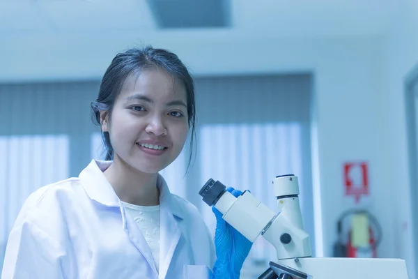 Young asian scientist looking through a microscope in a laboratory.Thailand people doing some research.