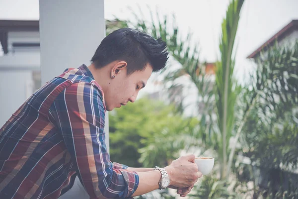 Handsome young man drinking coffee on the balcony, young modern, trendy,time for relax and rethink something of life,drink for fresh,vintage style,dark tone