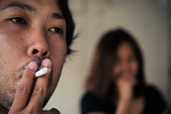 Passive smoking concept.Asian Man is smoking cigarette and woman is covering her face,No tobacco day,Smoking is objectionable to society,Thailand people