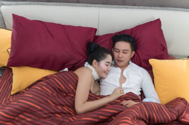 Genç Asyalı çift yatakta uyuyor ve sarılıyorlar.