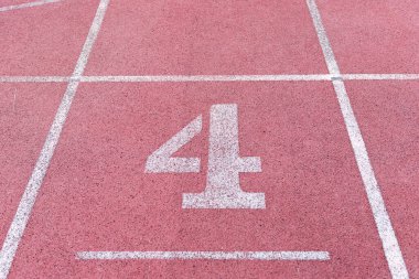 Kırmızı lastik yarış pistinde dört numaralı beyaz atletik pist, stadyumdaki koşu pistlerinin dokusu...