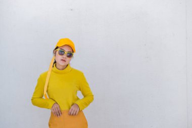 Güzel Asyalı kadın portresi, kirli beyaz duvarda sarı kumaşlar içinde, hippiler sarı şapka takıyor, Taylandlılar fotoğraf çekiyor.