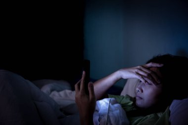 Asyalı kadın gece yatakta akıllı telefon oynar, Taylandlılar, sosyal medya bağımlısı, bütün gece internet oynar, Lychnobite