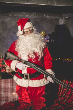 Evde Shortgun 'u tutan kızgın Noel Baba, sandalyeye otur ve çocuklara hediye paketi gönderme planını düşün.