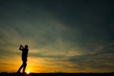 Siluet Asyalı golfçü güzel günbatımında golf oynuyor