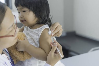Solunumunu ve kalbini kontrol etmek için steteskop kullanan Asyalı bir doktor, Taylandlı çocukların sağlığını kontrol ediyor.