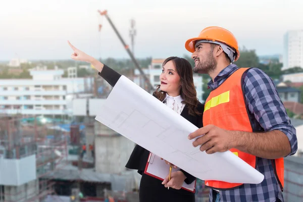 Asian engineer and business woman point finger up building under construction background,Thailand people,Point for looking building