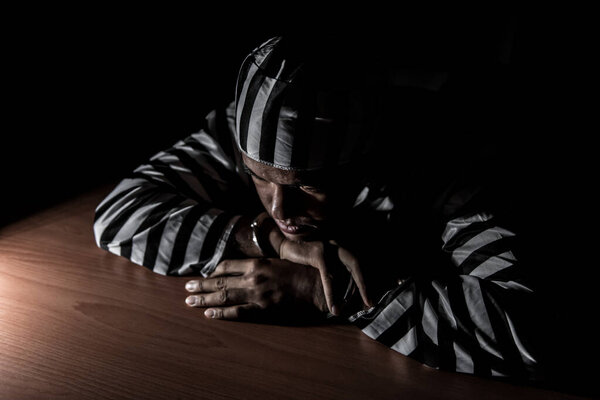 The suspect wear prisoner cloths was arrested at the investigation, interview to find out the truth, the thief was caught by the police come to the dark room,Thailand people,Knife in hand