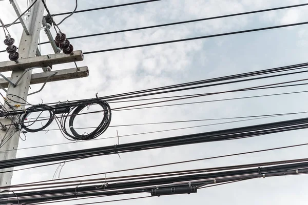 Bulutlu gökyüzü arkaplanındaki elektrik kabloları