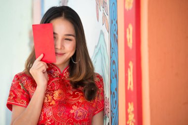 Mutlu Çin yeni yılı. Kırmızı zarflı geleneksel Cheongsam kıyafetleri giyen Asyalı kadın. 
