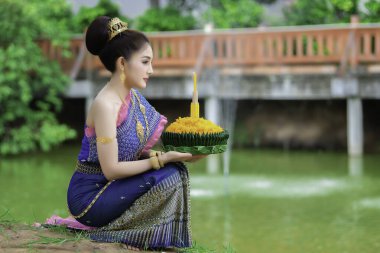 Tayland elbisesi içindeki güzel Asyalı kadın portresi geleneksel dua Kratong 'u, Tayland' da düzenlenen loy kratong festivaline katılması için tutuyor.