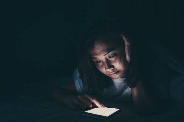 Asyalı kadın gece yatakta akıllı telefonla oyun oynuyor, Taylandlılar, sosyal medya bağımlısı.