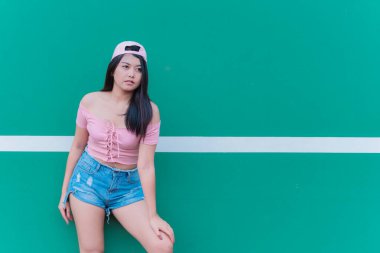 Güzel Asyalı şık bir kızın portresi siyah bir elbise giyer. Duvarda fotoğraf çeker. Tayland gençlerinin yaşam tarzı, modern kadın mutlu konsepti.