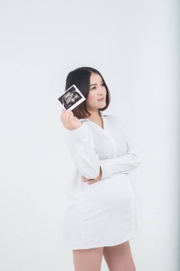 Beautiful asian pregnant woman with ultrasound photo in her hand on white background,Thailand people clipart