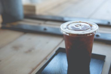 Bardakta buzlu kahve, ahşap masa üzerinde tüp, kahve dükkanında klasik tarzda.