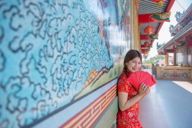 Cheongsam elbiseli güzel Asyalı kadının portresi elinde kırmızı bir zarf Taylandlı insanlar mutlu Çin yeni yılı konsepti