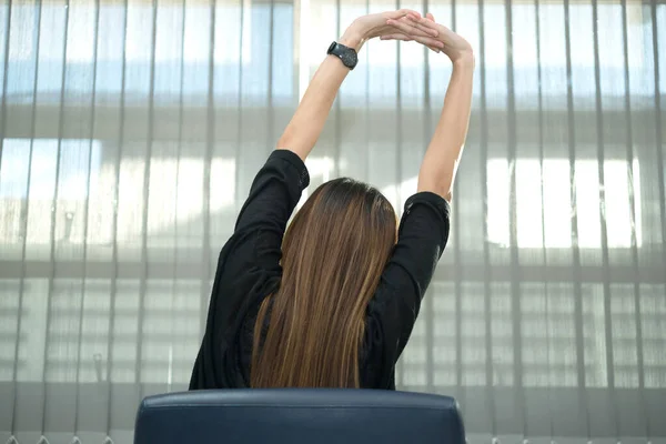 Asian officer woman stretching body at the desk of office from back angle,Thailand people,Businesswoman tired from hard work